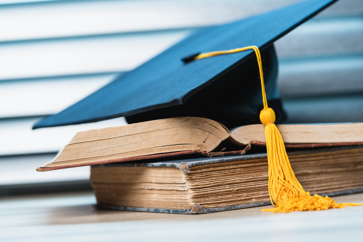 single black graduate cap on old books on the table background